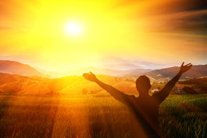 man waving his arms in front of a sunset