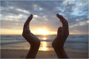 Hands framing sunrise in prayer